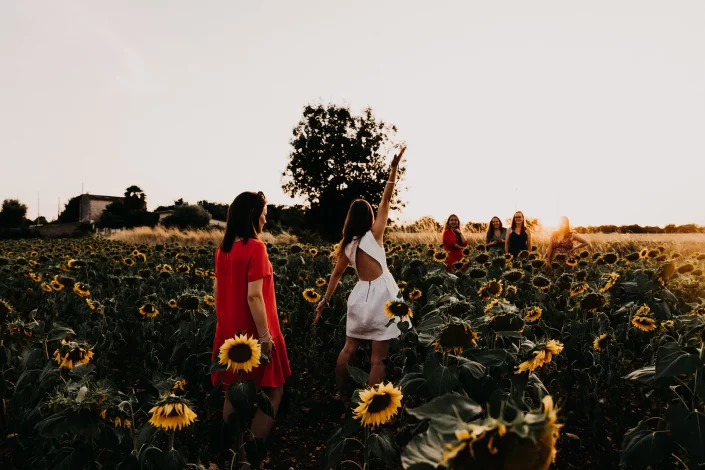 Séance photo entre amies dans un champ de tournesol au coucher de soleil
