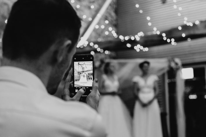 Invité qui prend les mariées en photo pendant la cérémonie - mariage Bois Menias